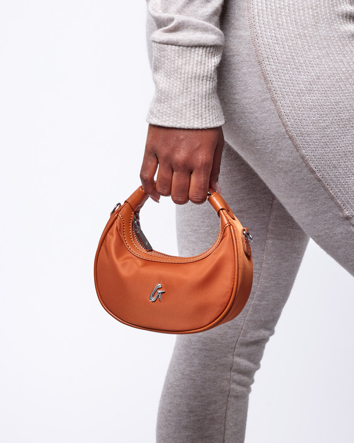 Brown nano nylon hobo bag held by a person in a gray outfit, showcasing its sleek design and stylish appeal.
