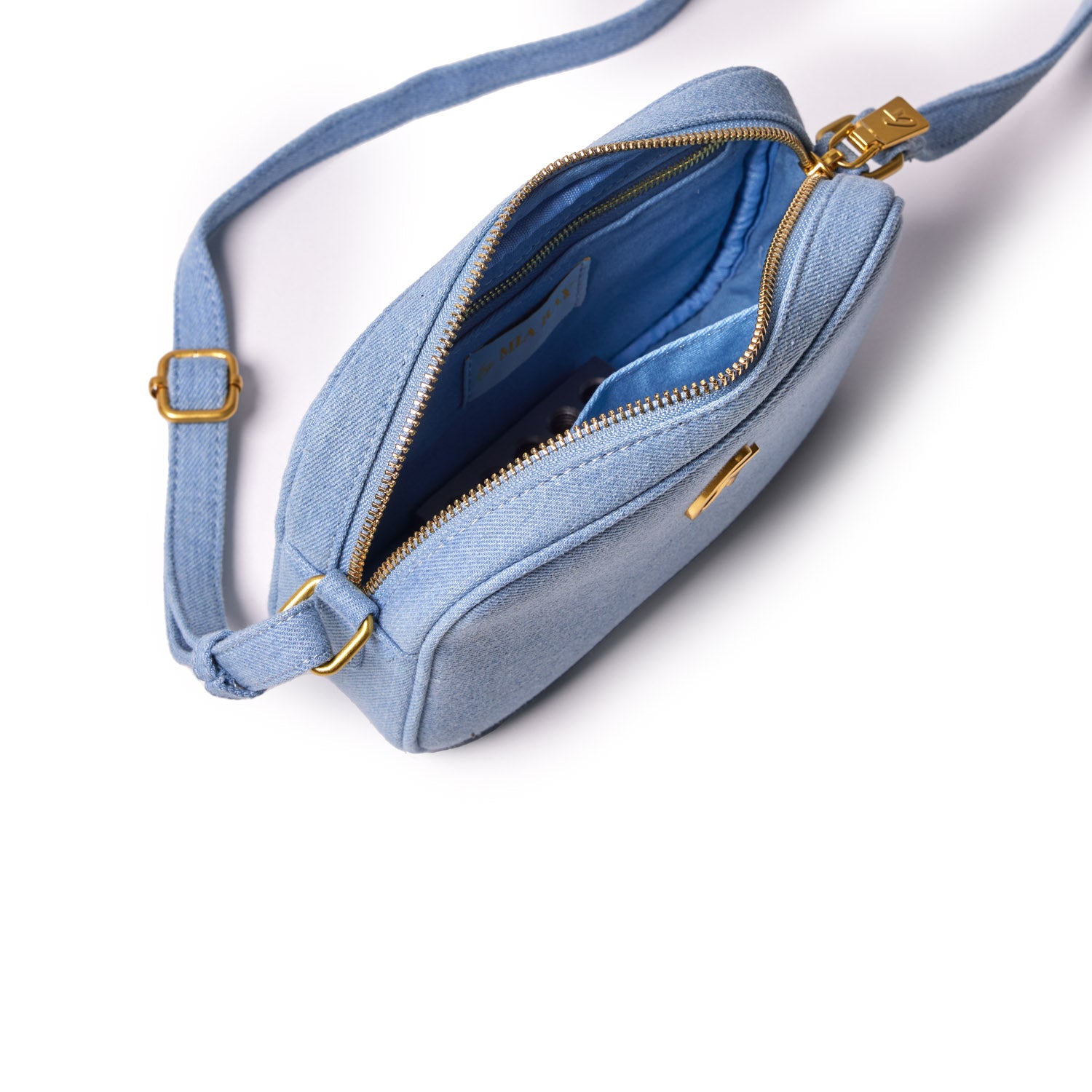 Mini denim gold camera bag with a zippered top, adjustable strap, and a spacious interior lined in blue fabric.