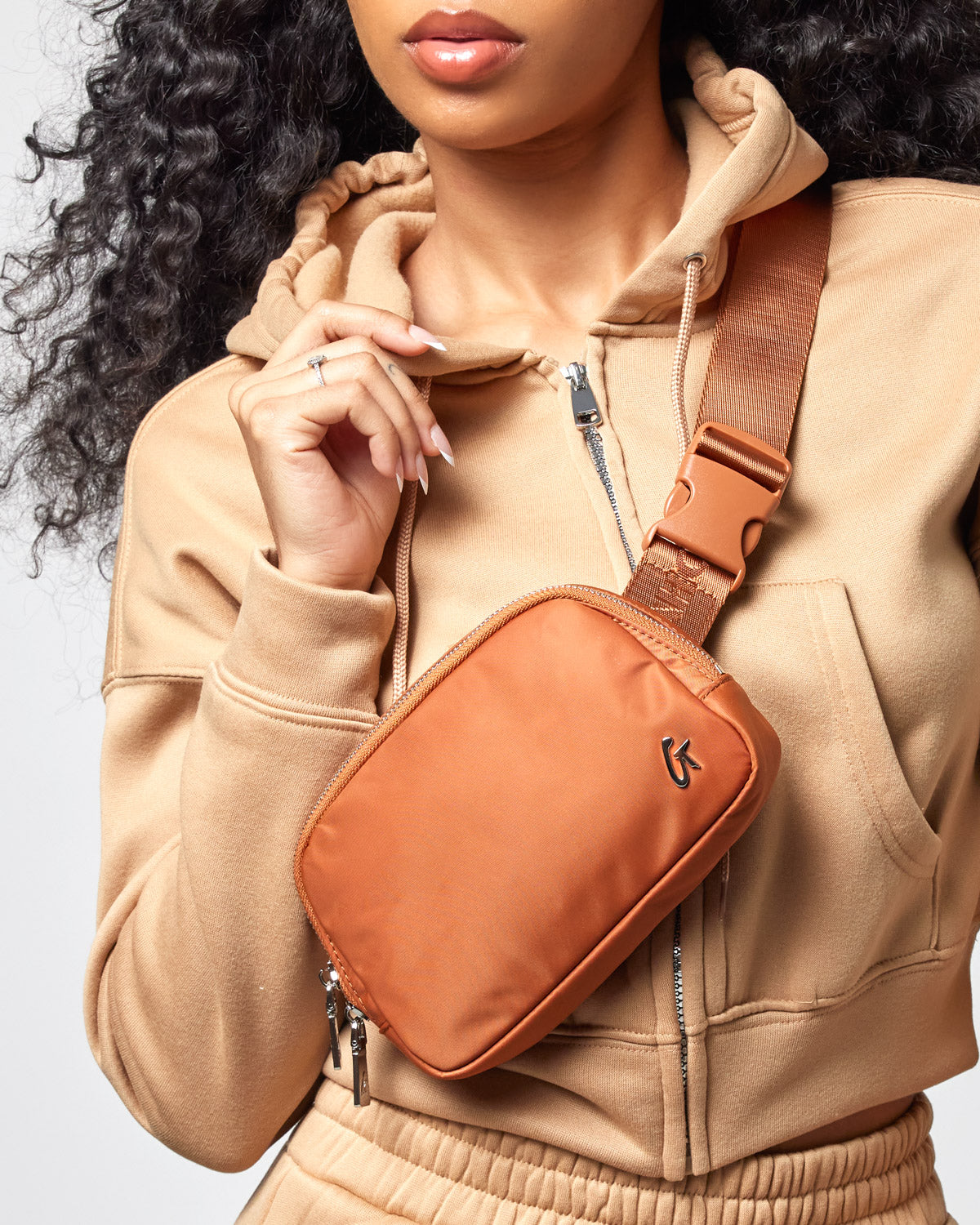 Nylon brown fanny pack worn across the chest with adjustable strap, featuring a small logo and zipper closure.