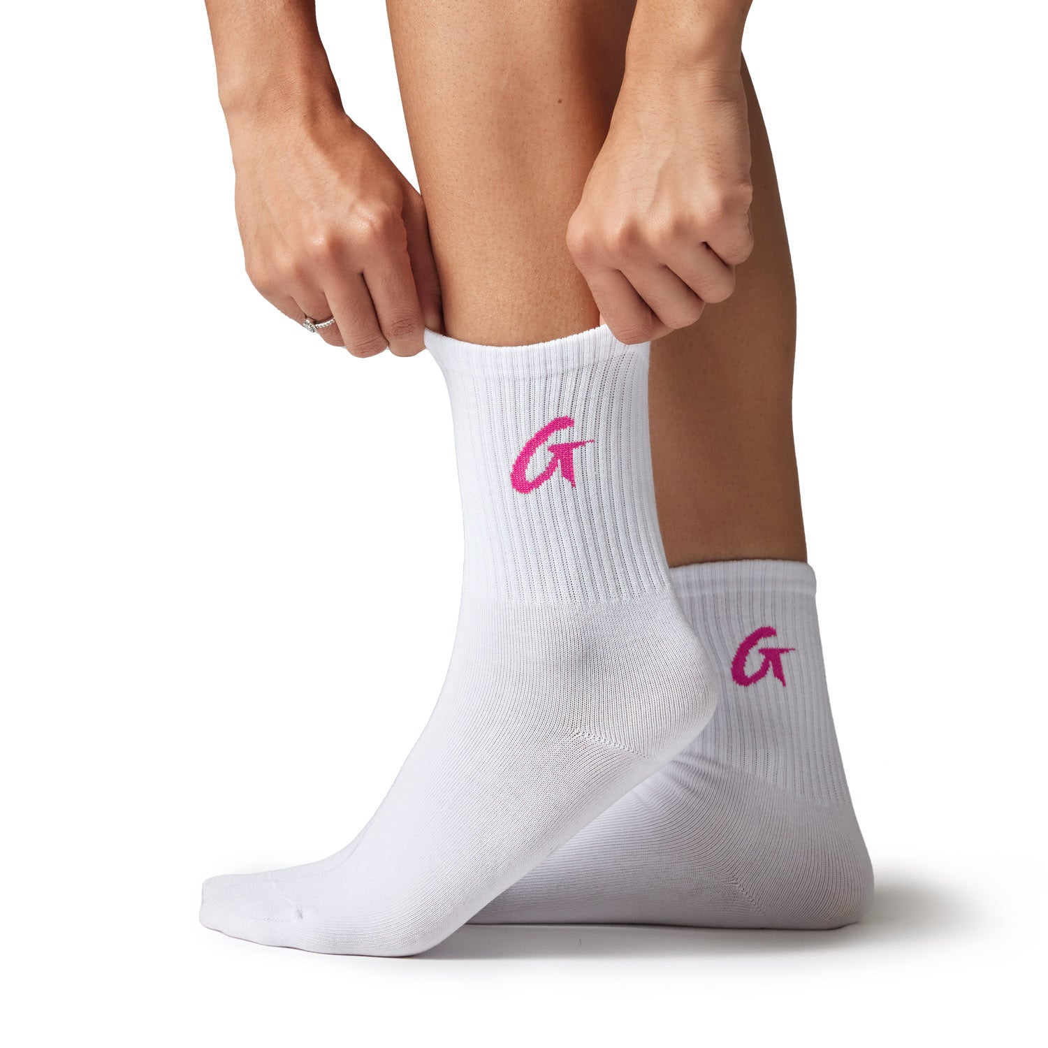 White crew socks with pink embroidered "G" logo, styled on a person kneeling and adjusting the sock.