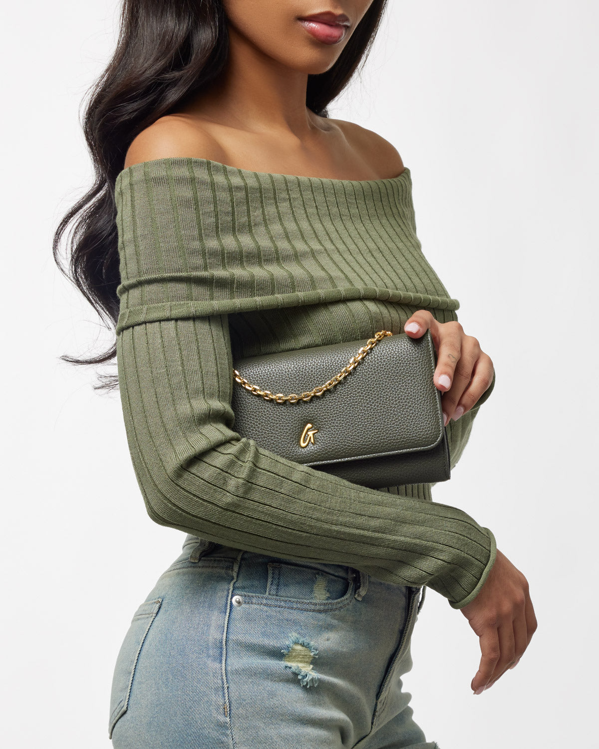 Olive green Pebble Travel Wallet on Chain (WOC) with gold chain detail, held by a woman wearing a matching off-shoulder top.