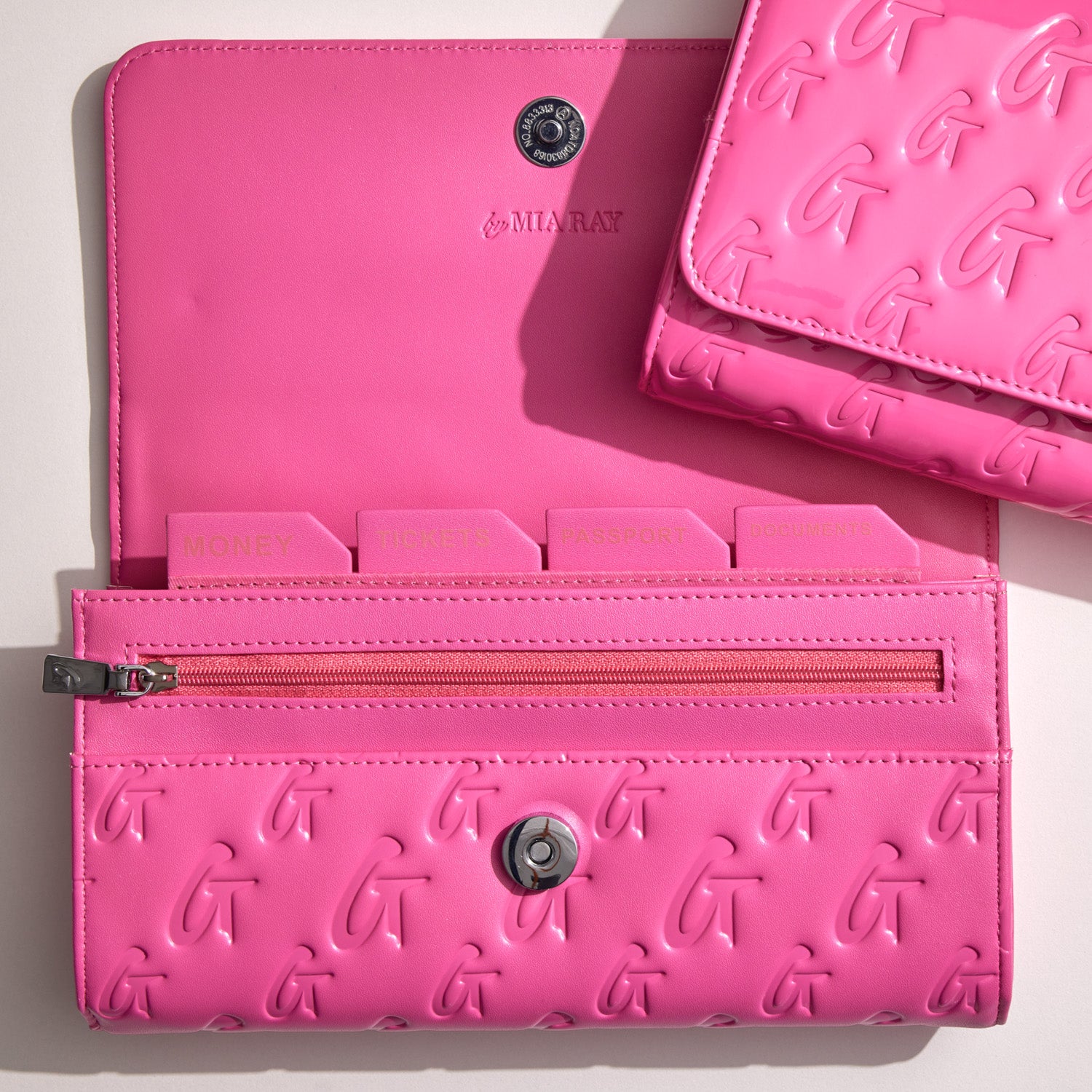 Bright hot pink travel wallet with embossed G pattern, multiple compartments, a zipper pocket, and a snap closure.