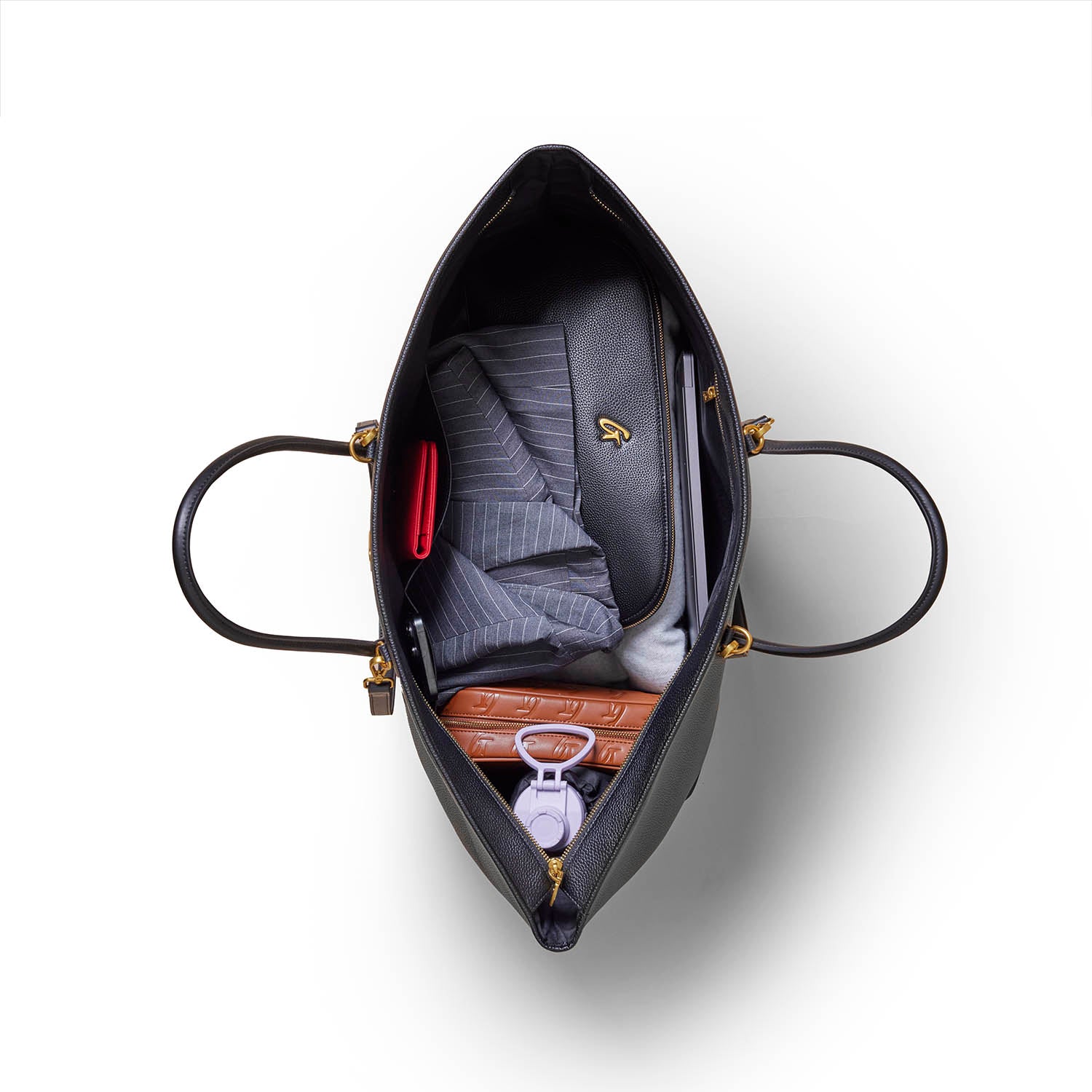 Open black tote bag with large pebble texture, gold hardware, and interior organized with pockets and items inside.