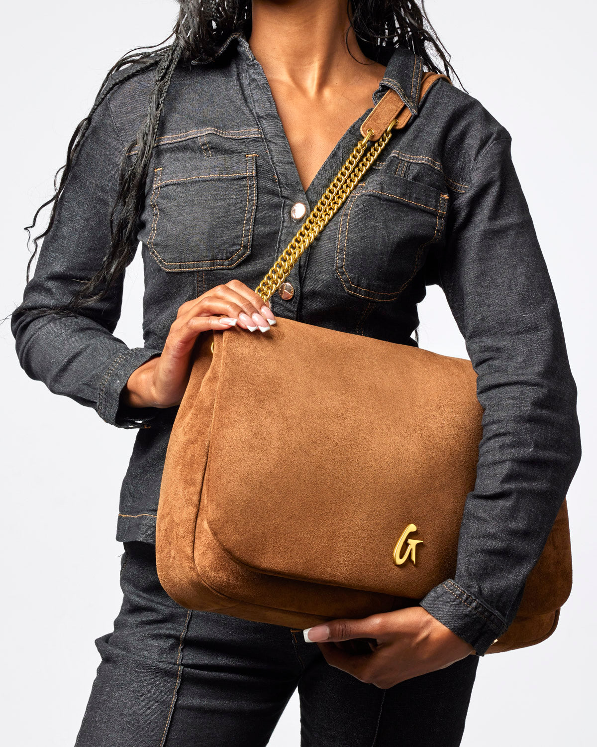 Large brown suede flap bag with a gold logo, styled with a chic denim outfit. Ideal for affordable luxury.
