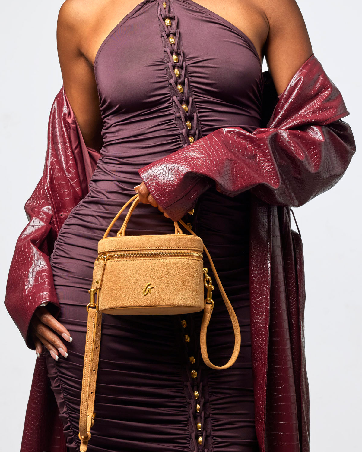 Tan mini suede vanity bag held by a model in a stylish outfit, showcasing affordable luxury and trendy design.