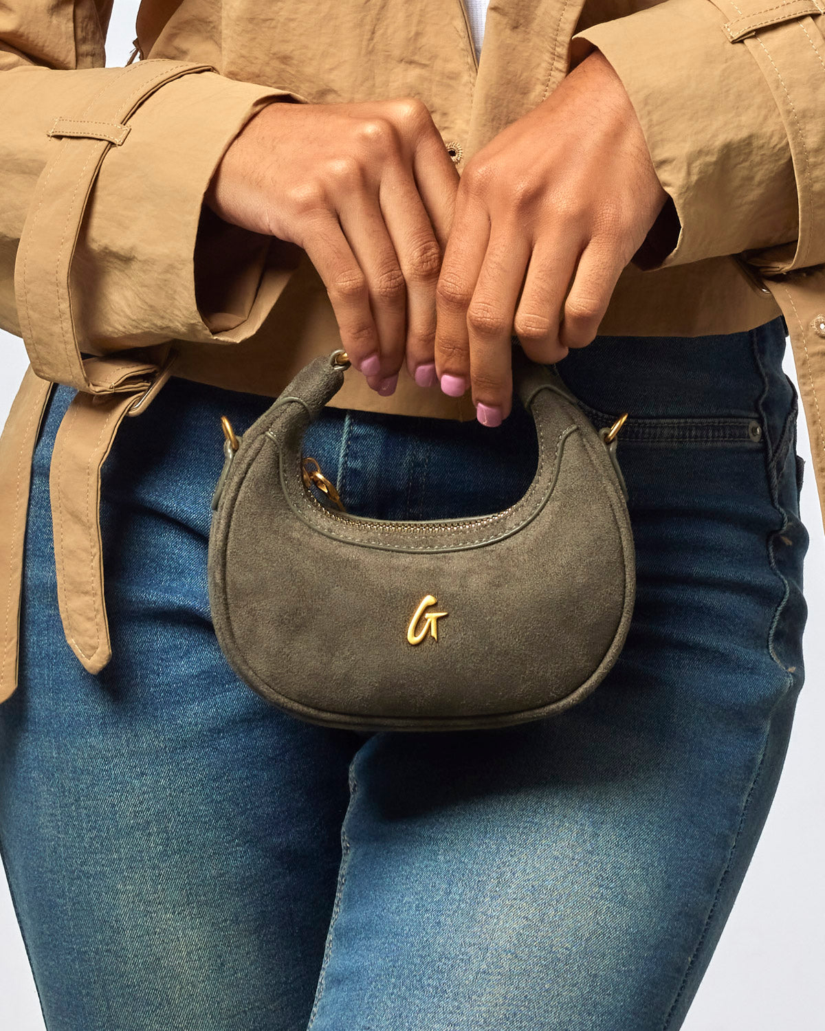 Olive green nano suede hobo bag held by a woman, featuring a gold logo and stylish design for affordable luxury.