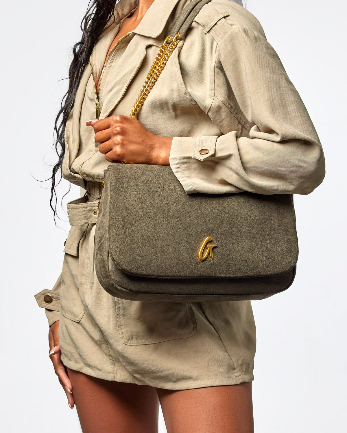 Medium olive green suede flap bag with a gold chain strap, styled with a neutral outfit. Perfect for chic, everyday use.