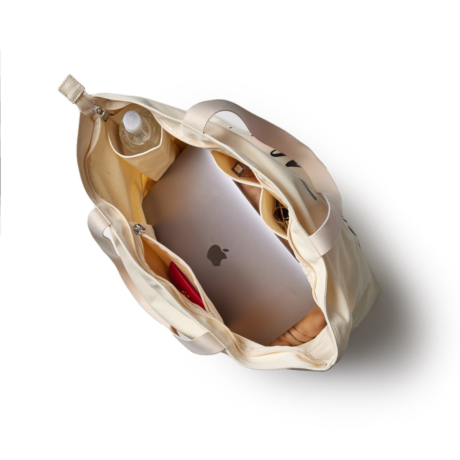 Purple canvas tote bag with signature logo, interior compartments holding a laptop, water bottle, and personal items.