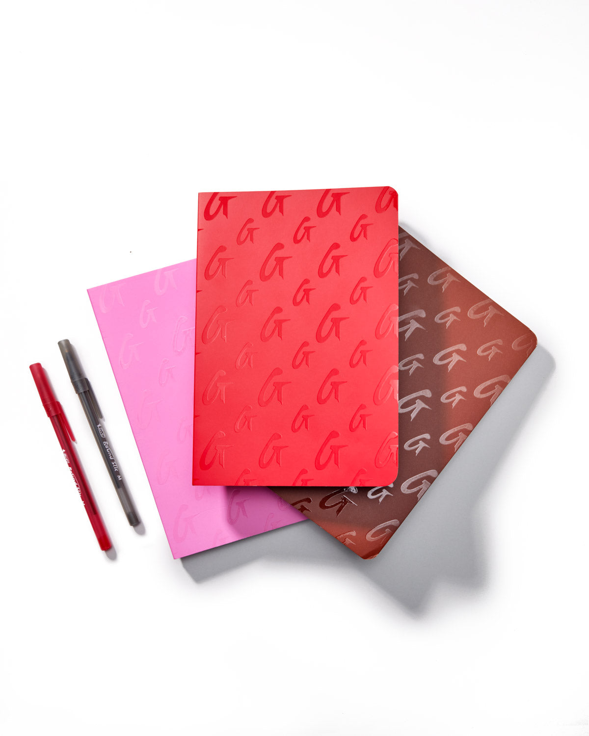 Hot pink Pebble Power Pack featuring three notebooks with embossed logos and two pens in coordinating colors.