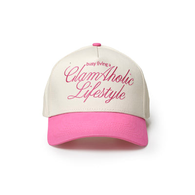 Hot pink trucker hat with white front and bold "busy living a GlamAholic Lifestyle" text. Perfect for stylish casual wear.
