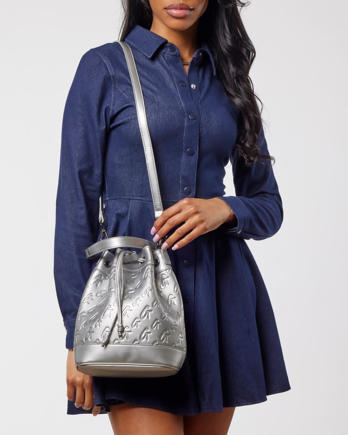 Medium monogram bucket bag in platinum, stylishly worn with a navy shirt dress, showcasing affordable luxury.