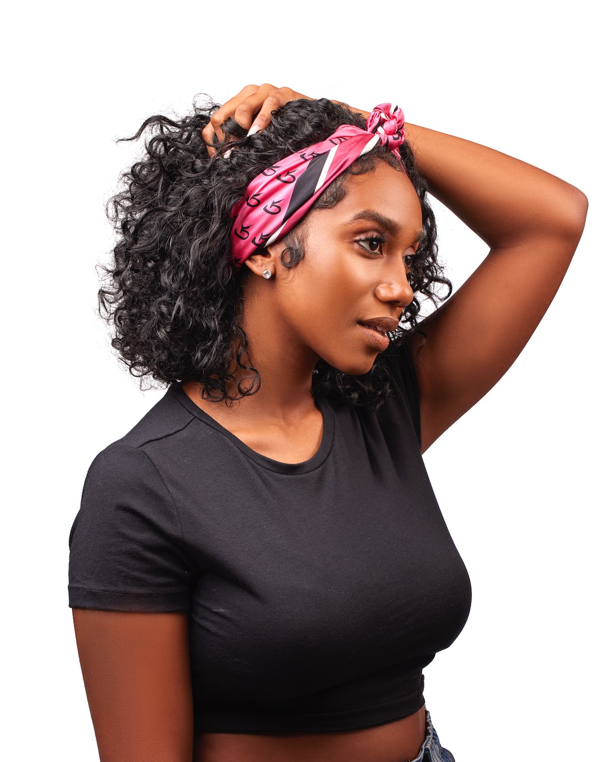 Woman wearing a black top with a hot pink silk scarf featuring a monogram pattern, styled as a headband.