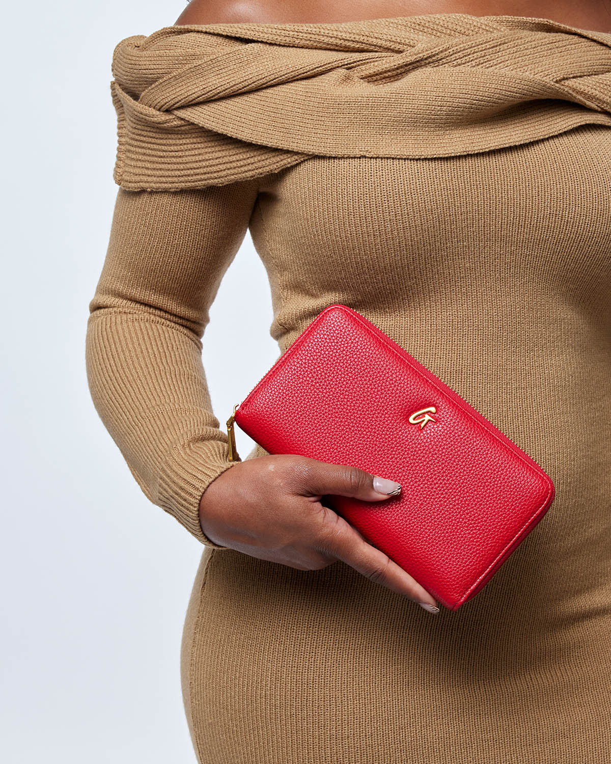 Red Pebble Power Pack held by a woman in a beige off-shoulder dress, showcasing its stylish design and functionality.