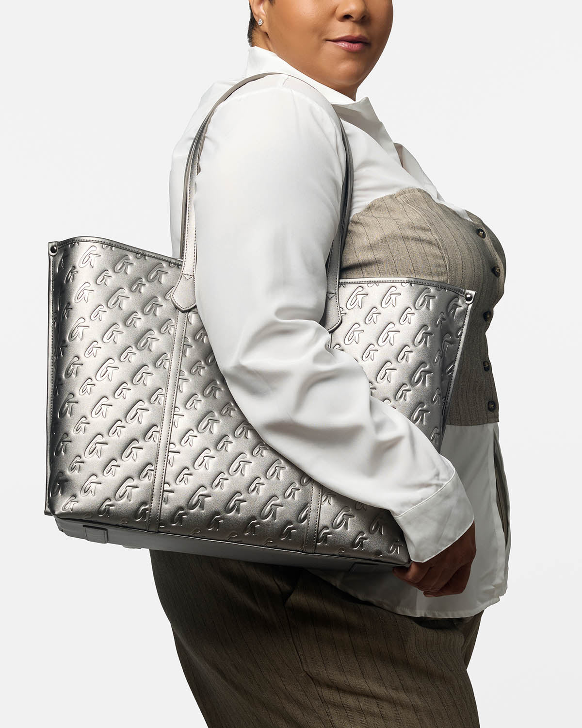 Sleek platinum XL monogram tote bag held by a woman, showcasing its stylish design and spacious interior.