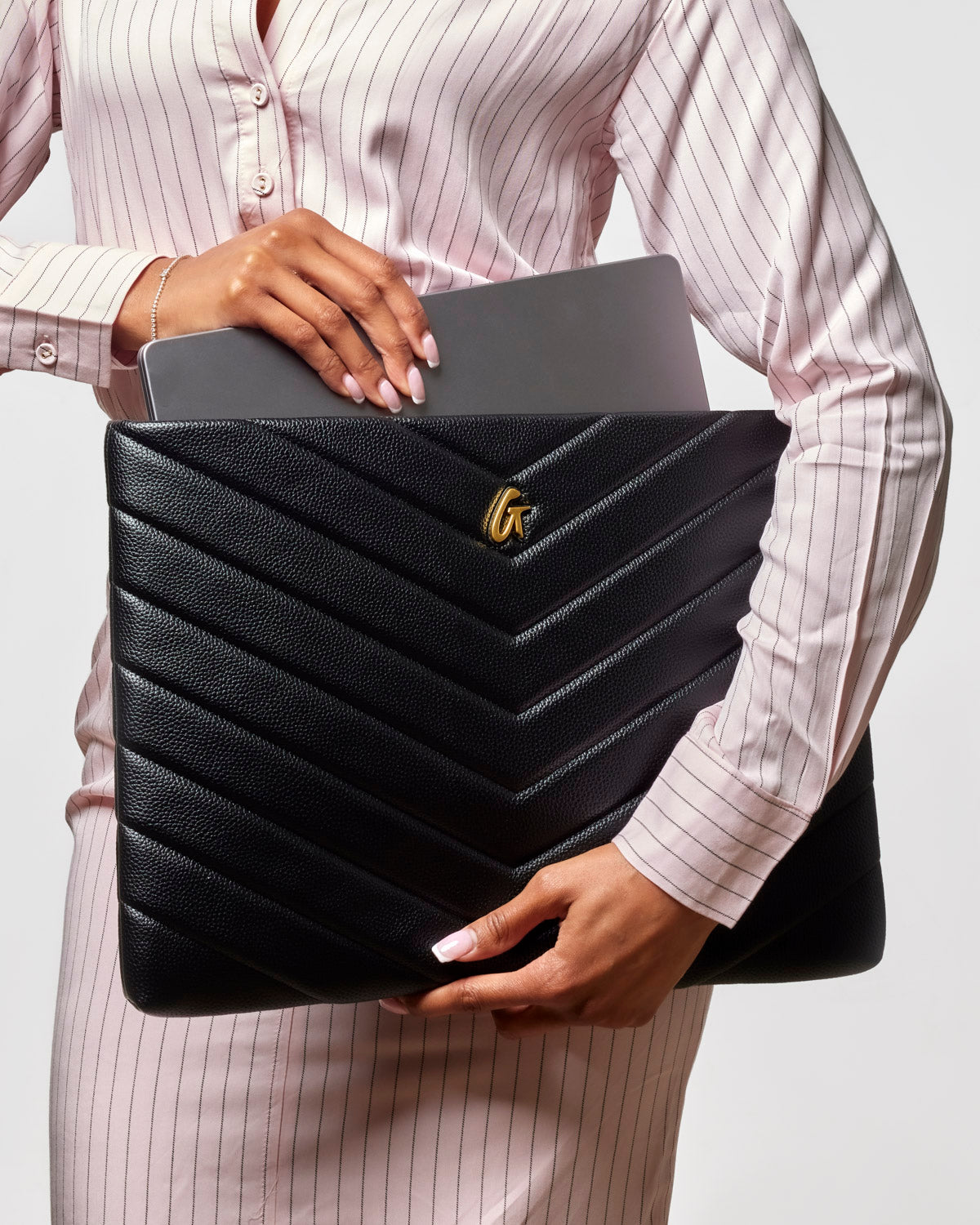 Black pebble laptop sleeve with chevron design, held by a woman in a striped shirt, showcasing stylish protection for laptops.