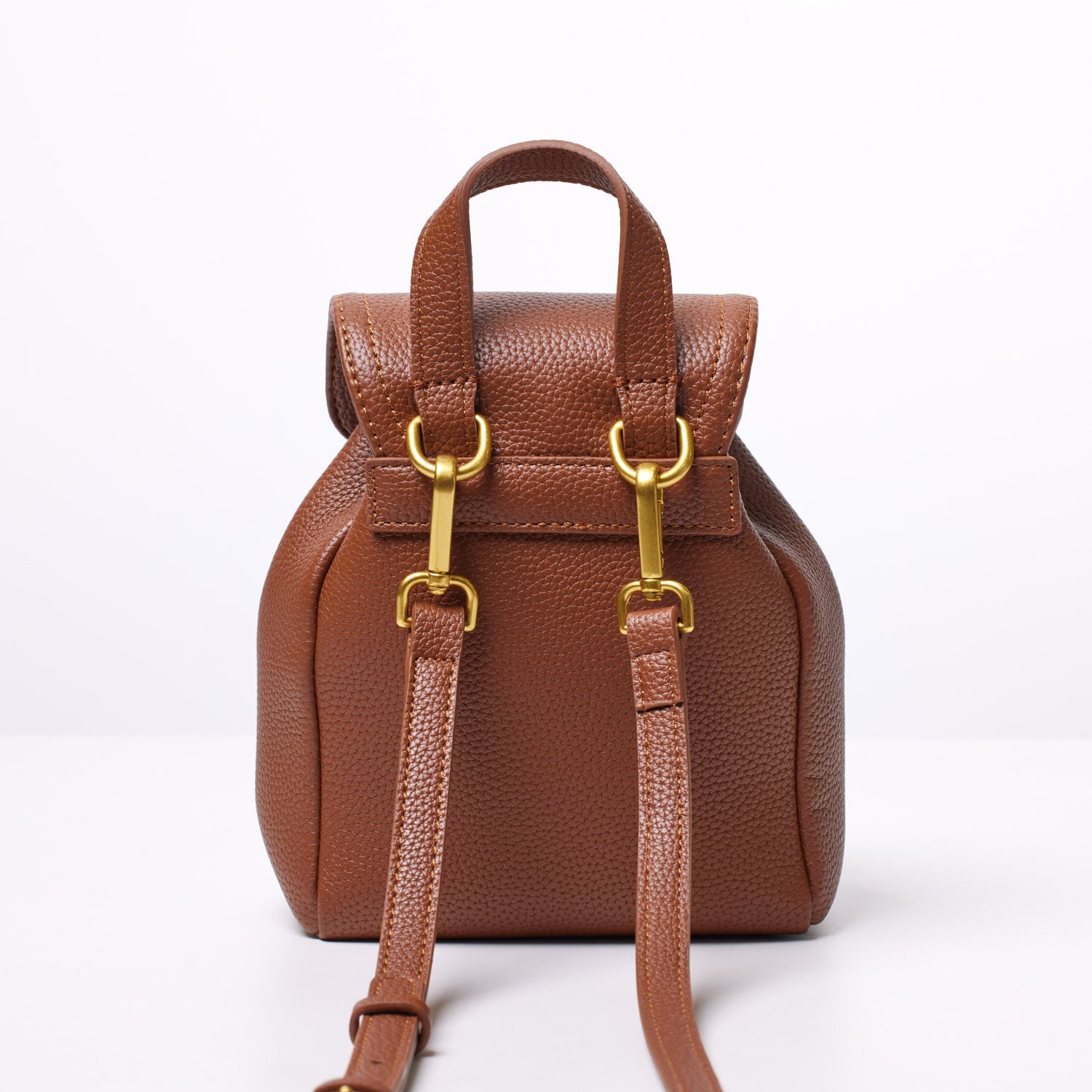 Small brown pebble-textured crossbody backpack with gold hardware, adjustable straps, and a top handle.