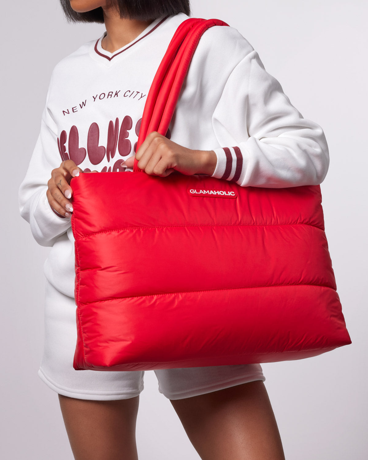 Red athletic nylon tote bag held by a person wearing a white sweatshirt, showcasing a stylish and functional design.