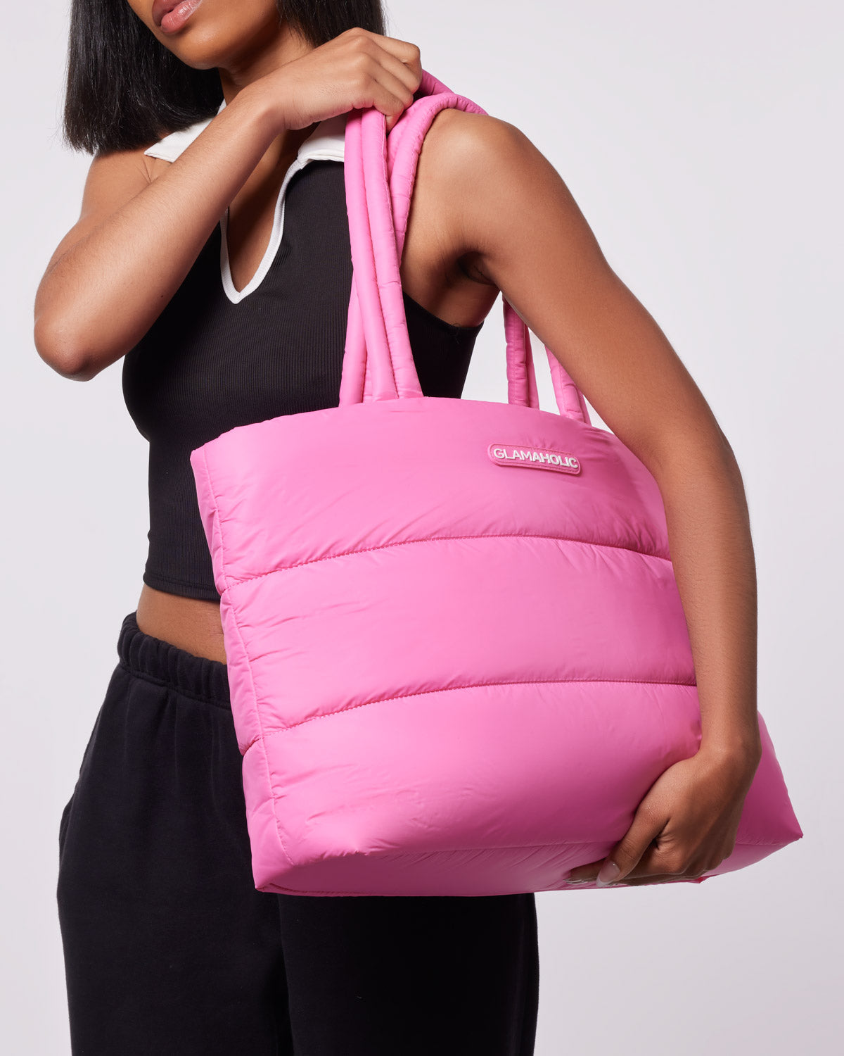 Hot pink athletic nylon tote bag held by a person wearing a black crop top and sweatpants, showcasing its stylish design.