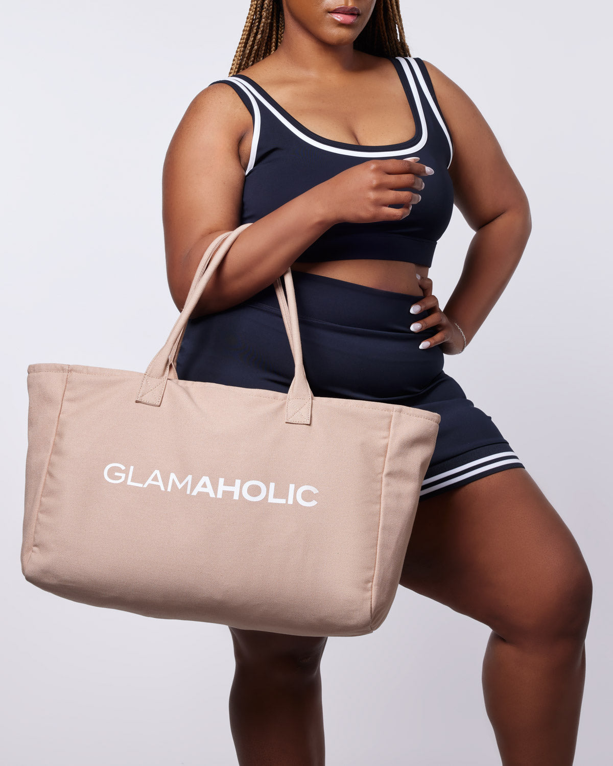 Athletic canvas tote in nude held by a model wearing a navy sports bra and shorts, showcasing a stylish and functional design.