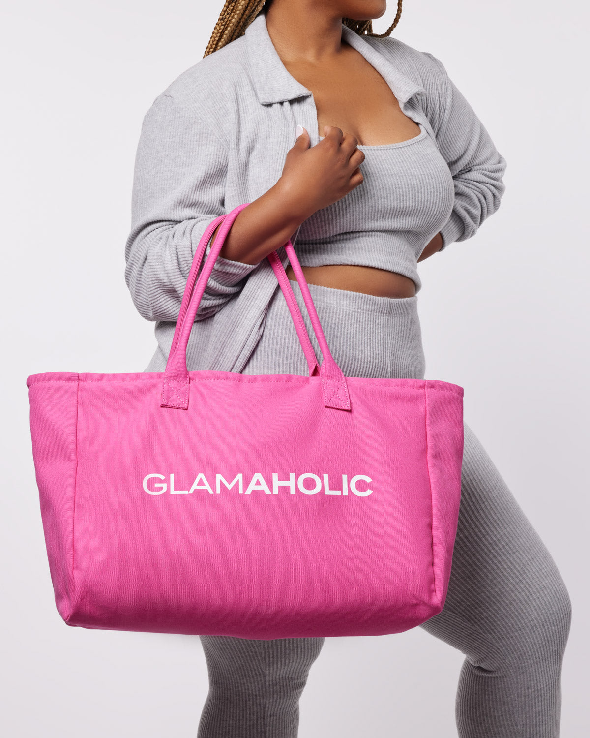 Hot pink athletic canvas tote bag with "GLAMAHOLIC" logo, modeled by a woman in a gray outfit.