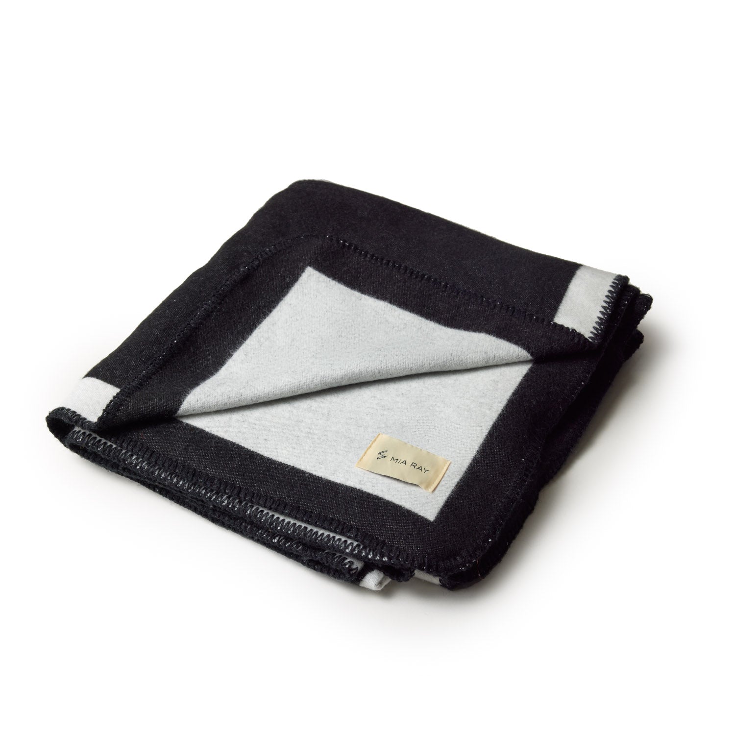 Black classic throw blanket, folded to show soft fabric and stitched edges, with a small beige label reading "MIA RAY.