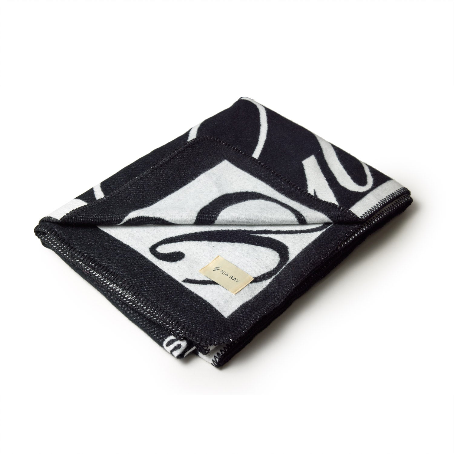 Black luxury throw blanket with a bold signature logo design, folded to showcase the stylish pattern and label.