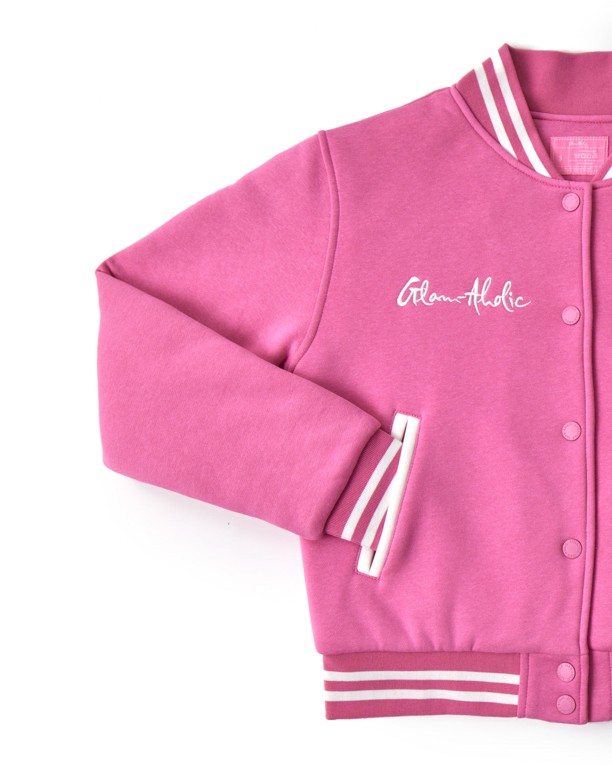 Pink varsity jacket with striped cuffs, embroidered "Glam-Aholic" logo, snap buttons, and ribbed collar and hem.