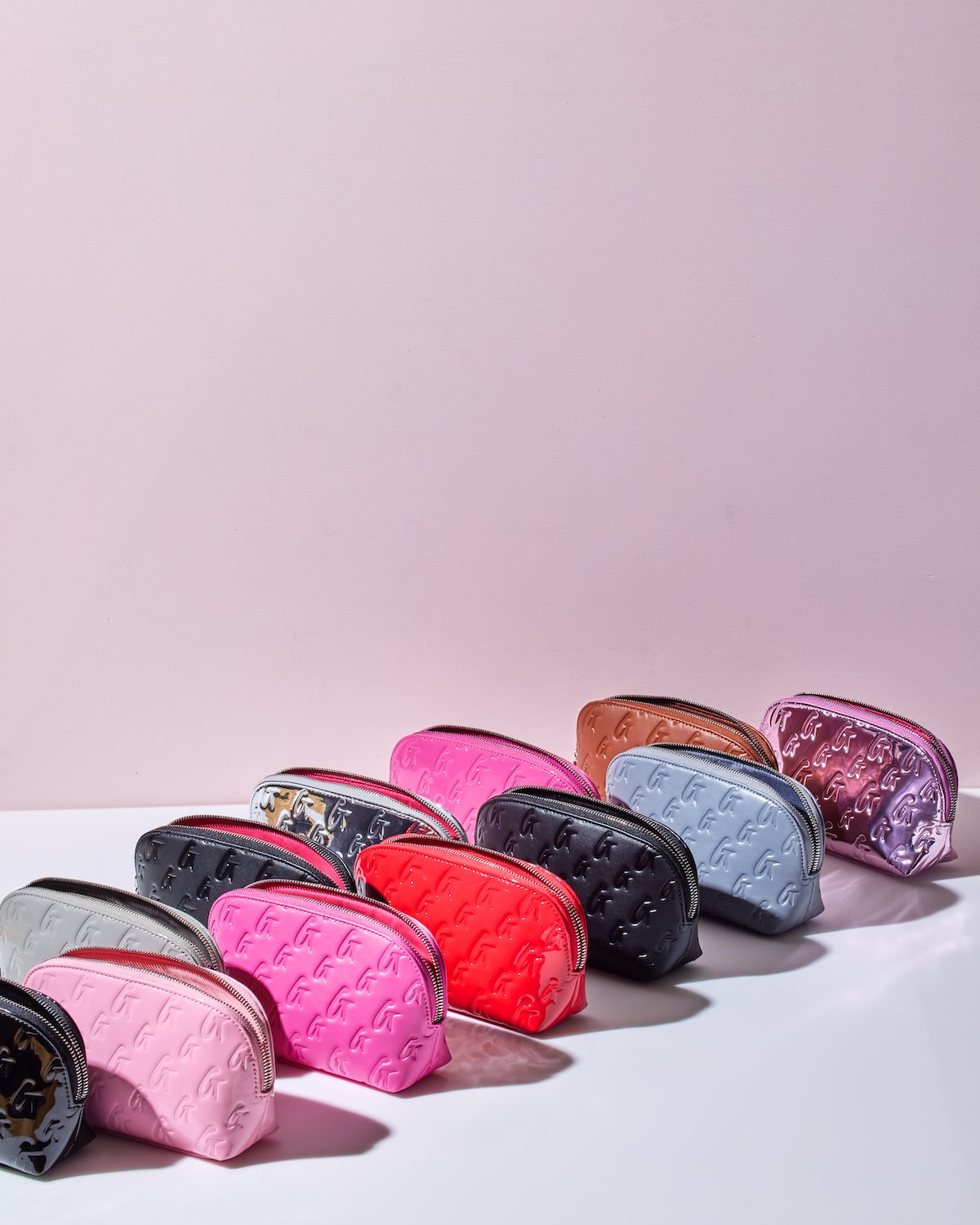 Gray monogram cosmetic pouch among a variety of colorful pouches, showcasing stylish and functional design.