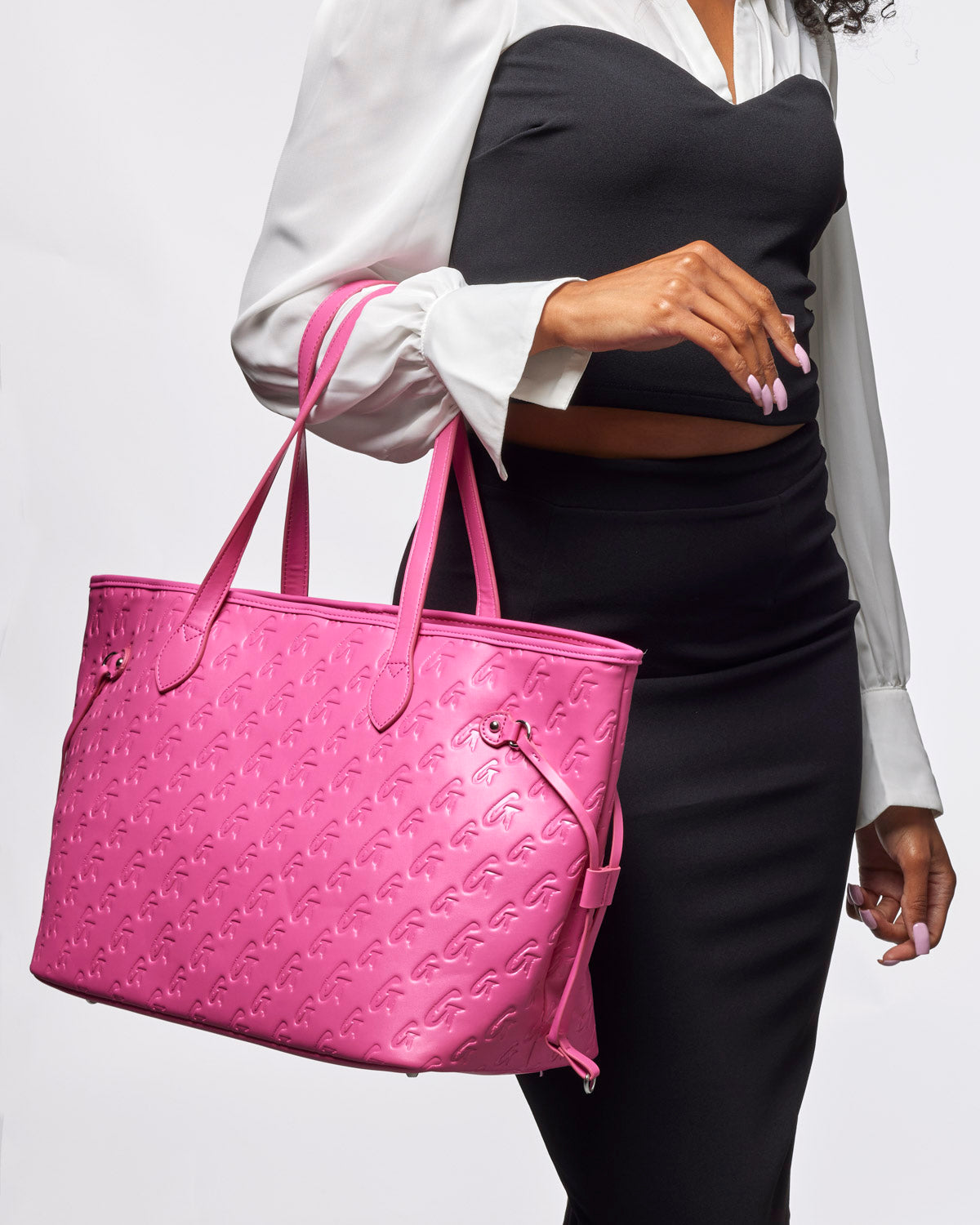 Hot pink monogram tote bag held by a woman, featuring a stylish embossed design and spacious interior for everyday use.