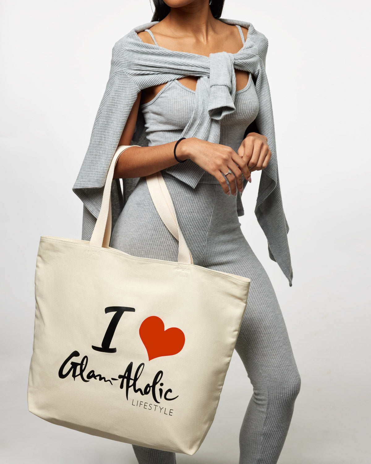 Red canvas tote bag with "I ♥ Glam-Aholic Lifestyle" printed in black and red, carried by a woman in gray clothing.