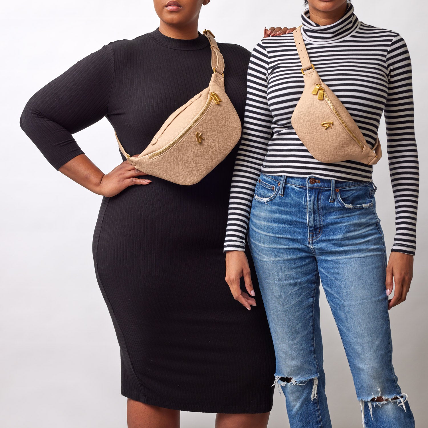 Two women wear beige pebble-shaped fanny packs with gold zippers and hardware, styled across their chests and hips.