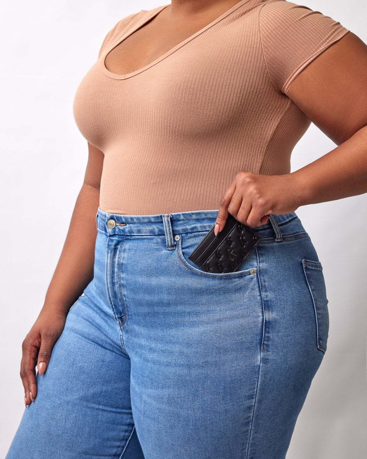 Black Monogram Gunmetal Card Holder partially visible in a woman's front pocket, held by her right hand.