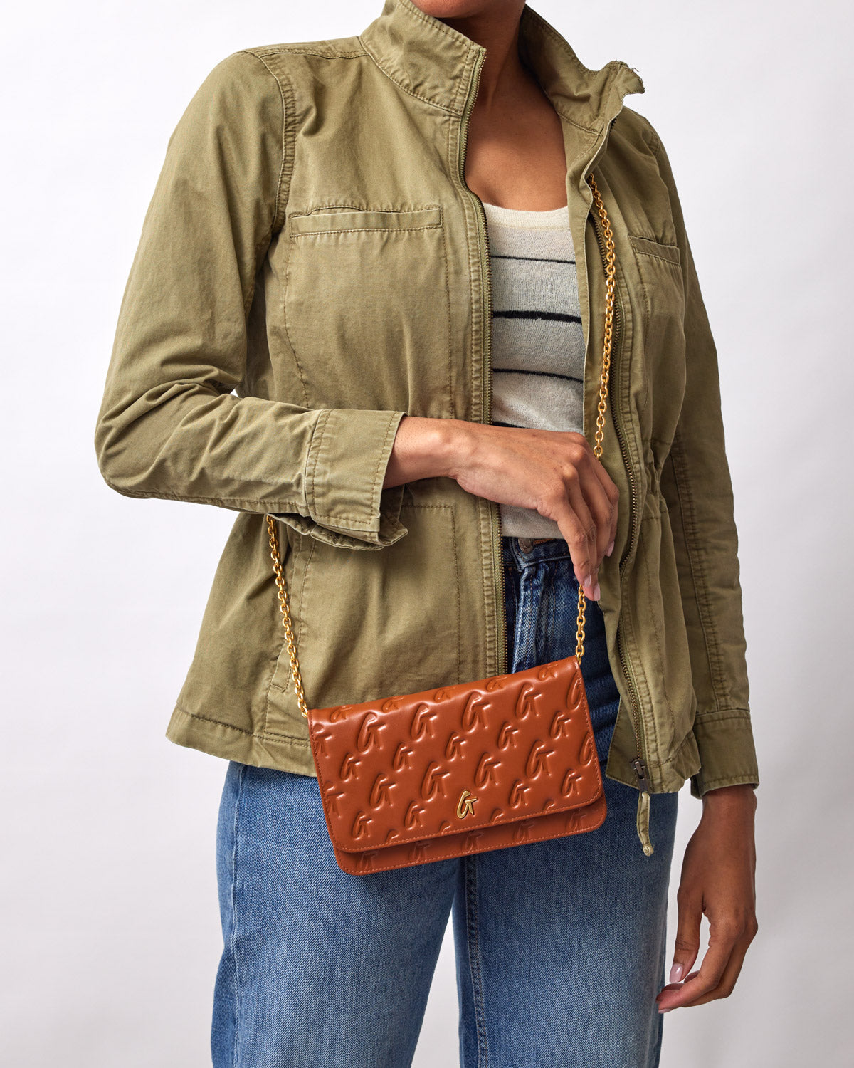 Brown Monogram Gold WOC shoulder bag with embossed logo pattern, gold chain strap, worn with casual outfit.
