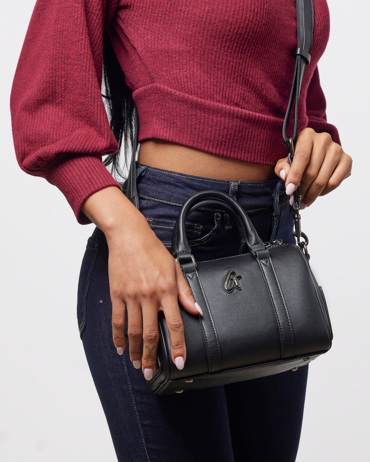 Mini Standard Gal Boston Bag in black, stylishly held by a woman in a red sweater and jeans, showcasing its chic design.