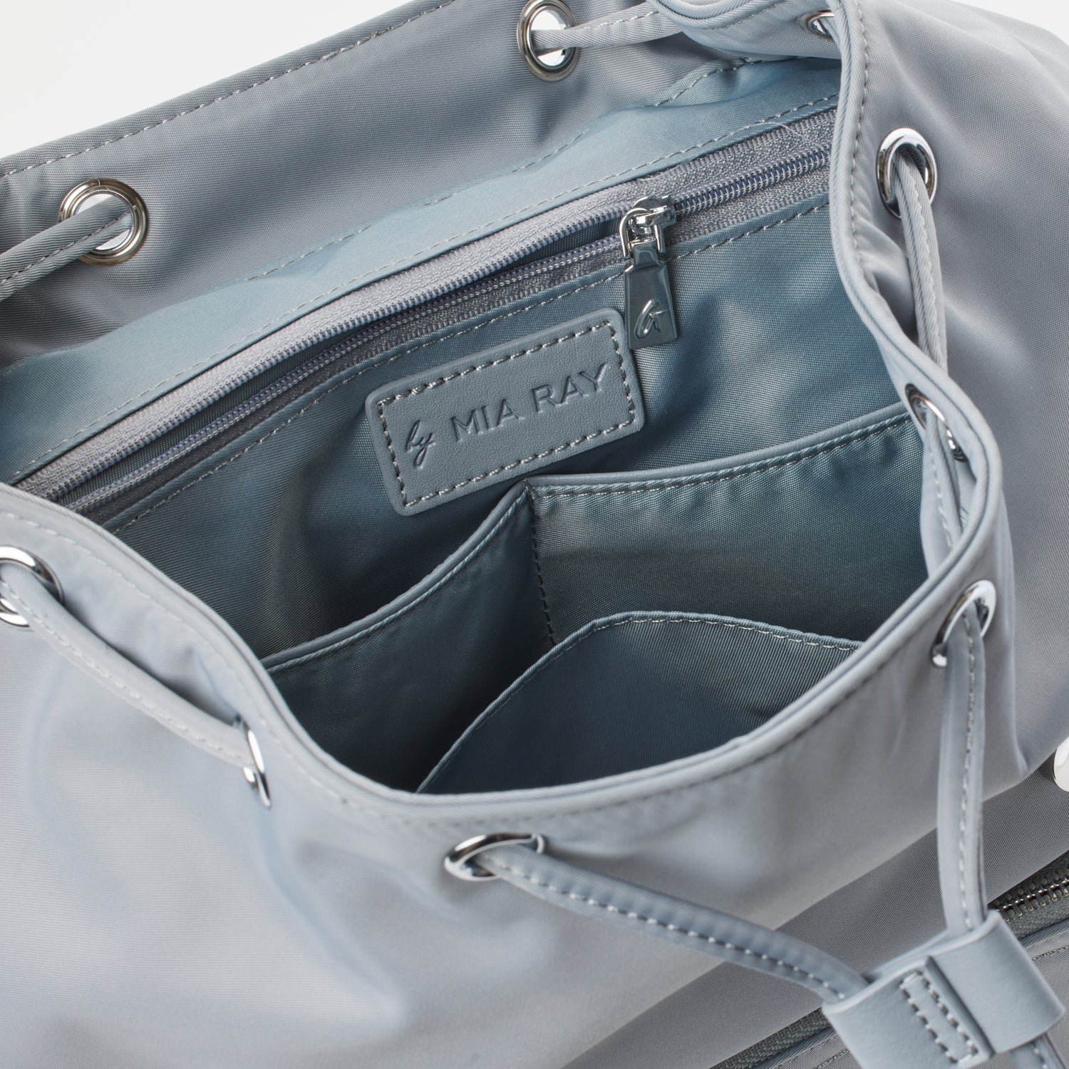 Gray nylon backpack with interior zippered pocket, multiple compartments, and metal grommet details.
