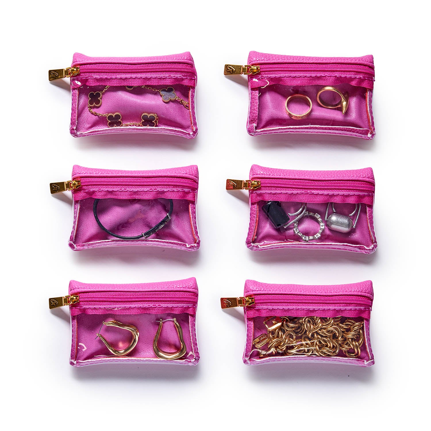 Six pink pebble jewelry cases with transparent fronts, each containing different jewelry pieces like rings, earrings, and chains.