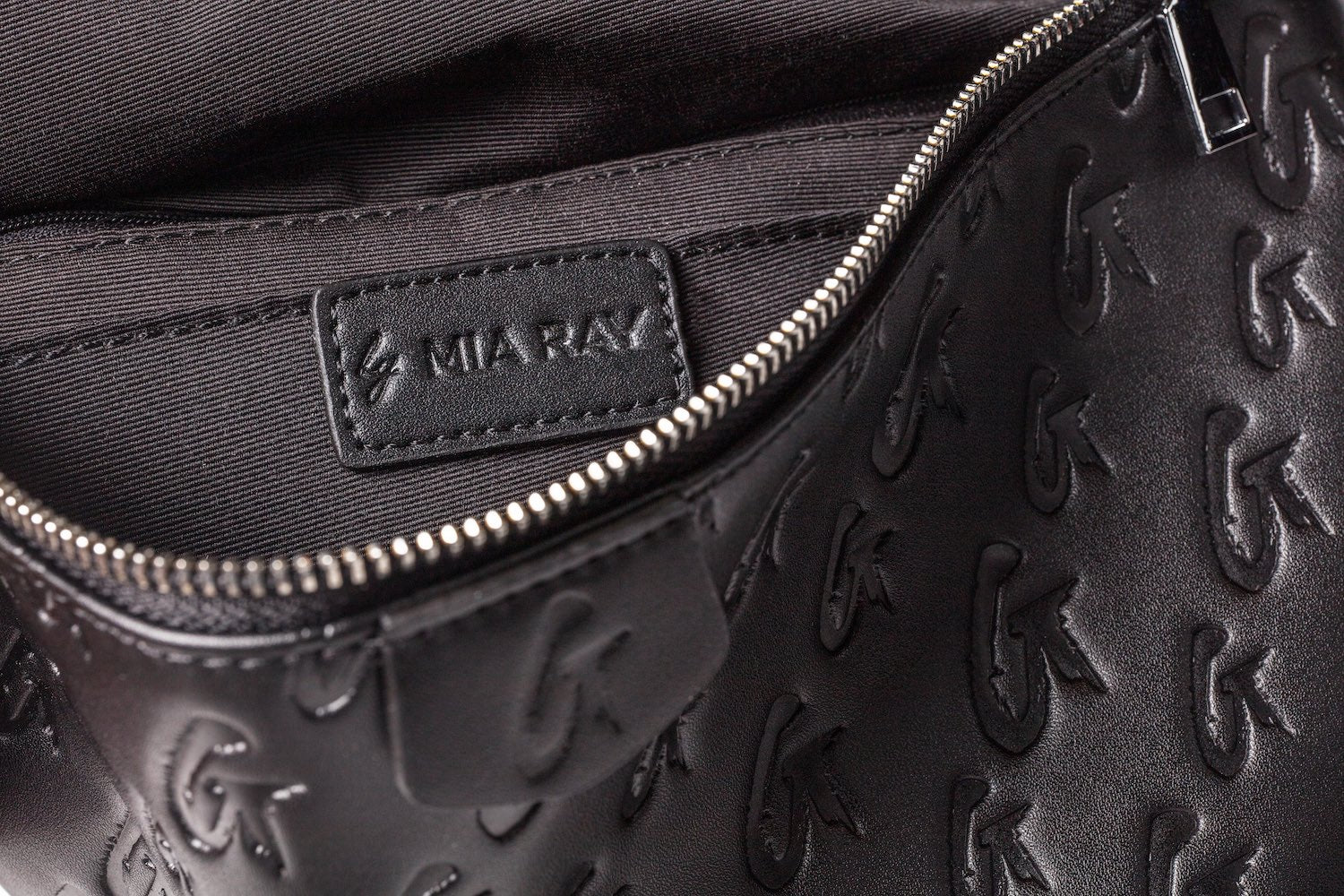 Close-up of a black Monogram Fanny Pack with embossed "CK" logo pattern, silver zipper, and interior label reading "MIRARAX.