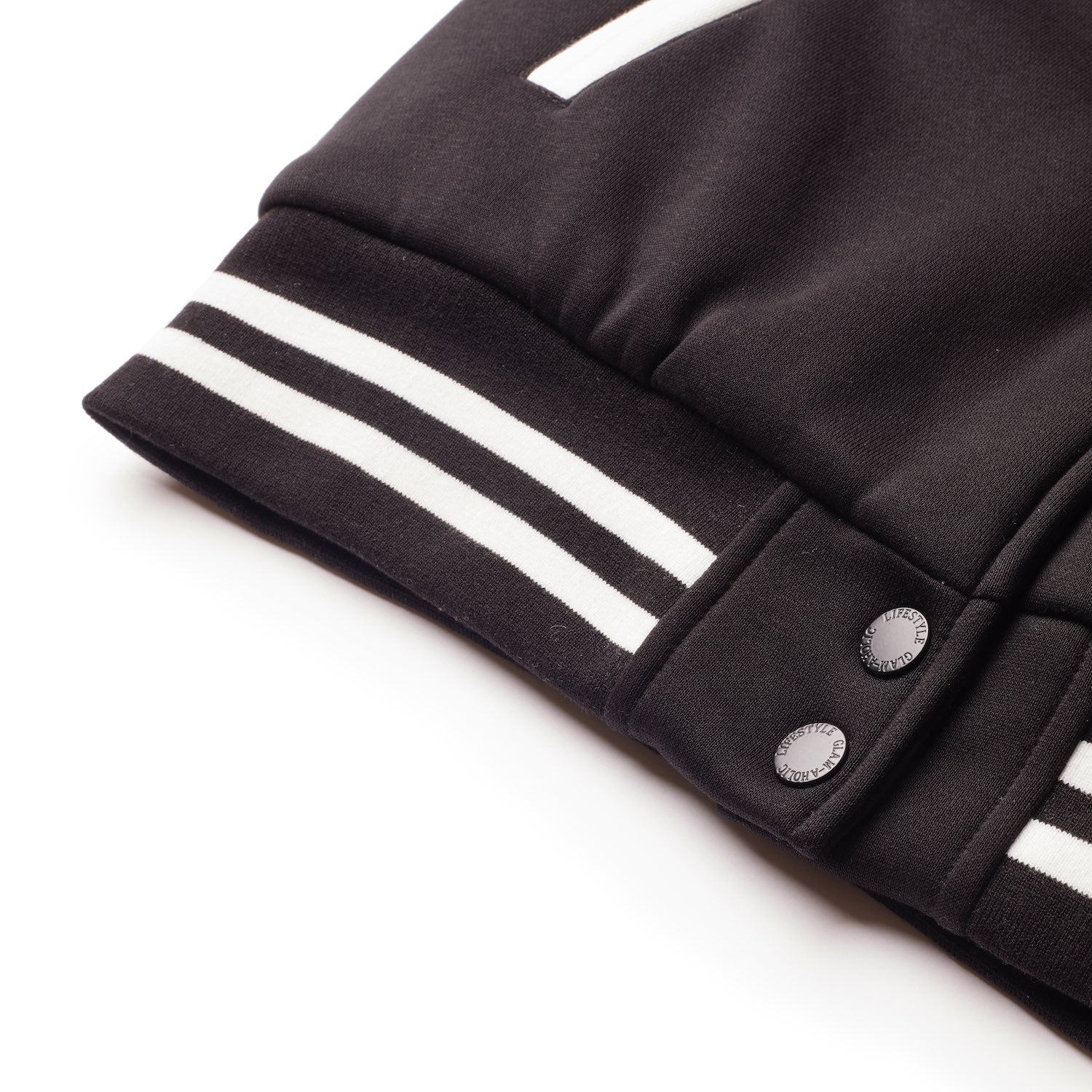 Close-up of a black varsity jacket with white striped cuffs and metal snap buttons, showcasing a sleek, sporty design.