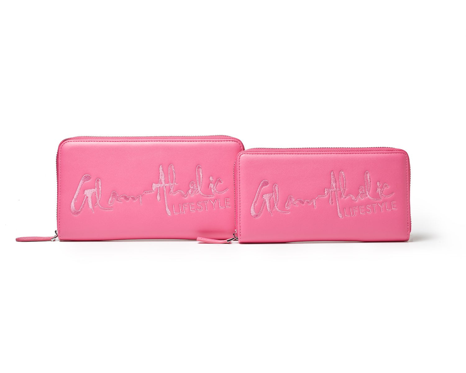 Two pink wallets with "Glamathic Lifestyle" embroidered in cursive, featuring a large signature logo and zip closures.