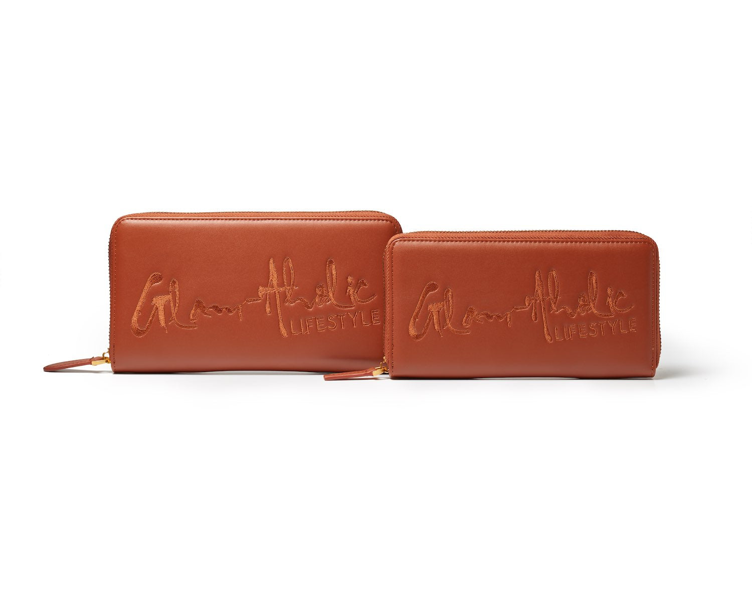 Brown signature logo wallets, one large zip-around and one smaller, with embossed "Glamatic Lifestyle" text.